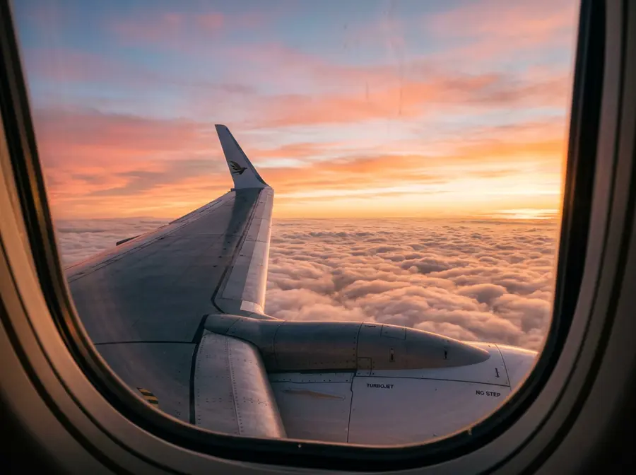 Airplane wing above the clouds at sunset